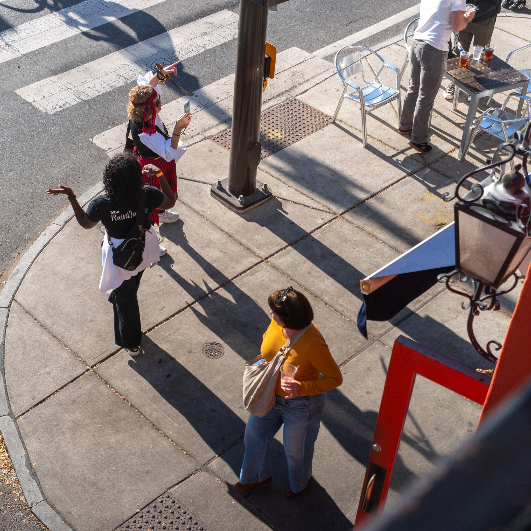 A passerby in motion with a crosswalk and curb, photographed from a rooftop angle.