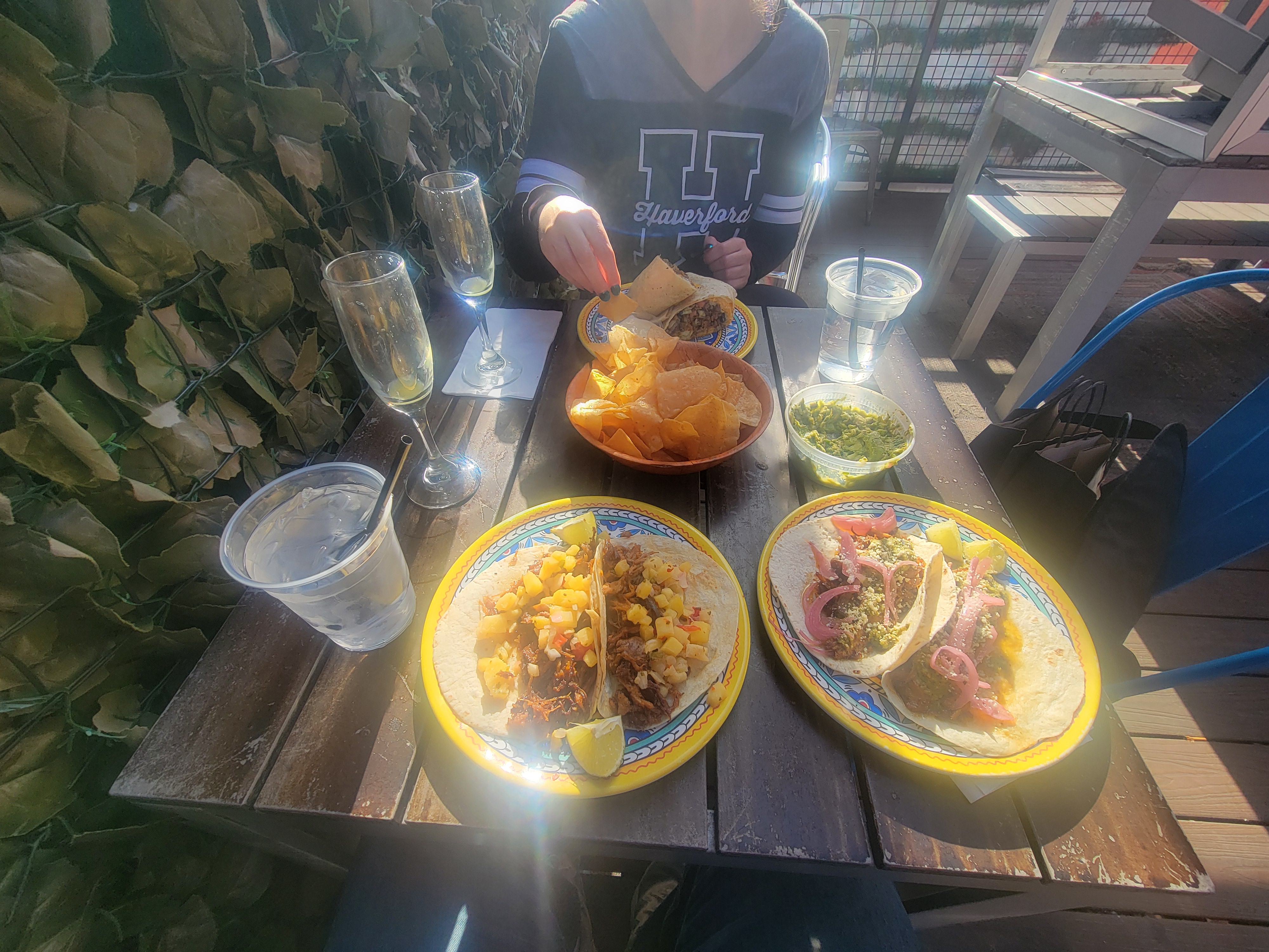 Table spread at La Roca with tacos, chips, salsa, and sparkling glasses under soft afternoon light.
